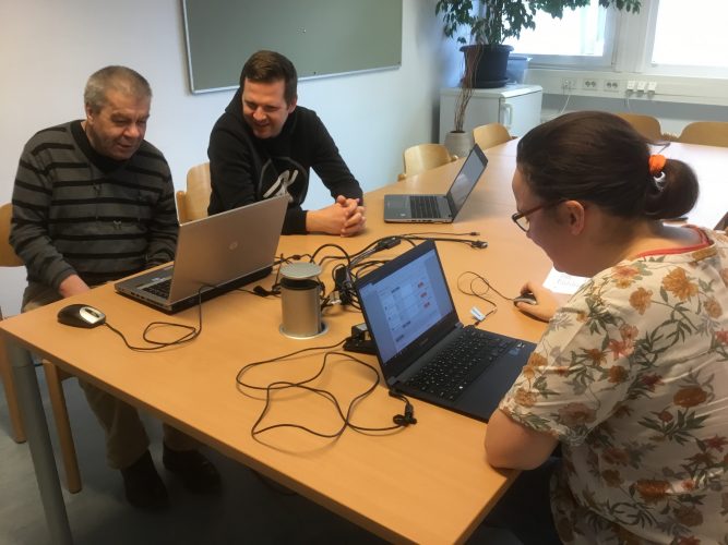 two Peer Researcher sitting at a table with their laptops , an observer is sitting next to one of the peer researchers