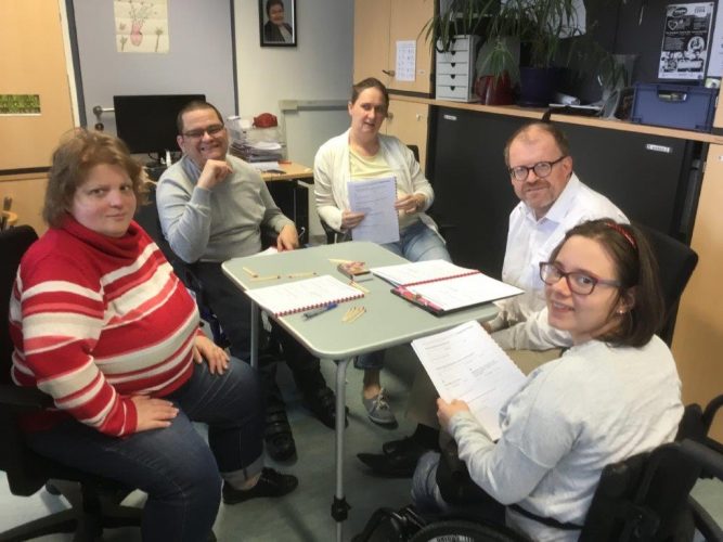 3 female and 2 male peer researchers sitting around a table and testing Easy Reading on paper