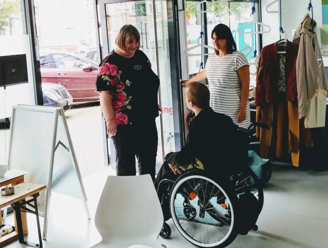 Man in wheelchair greets woman entering through PIKSLs door