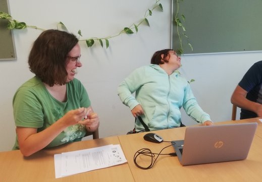 Two female easy reading members sit laughing at the table