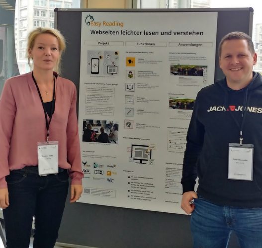 Man and woman standing in front of an Easy Reading Poster