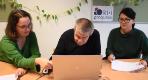 Two women and a man sit in front of a laptop.