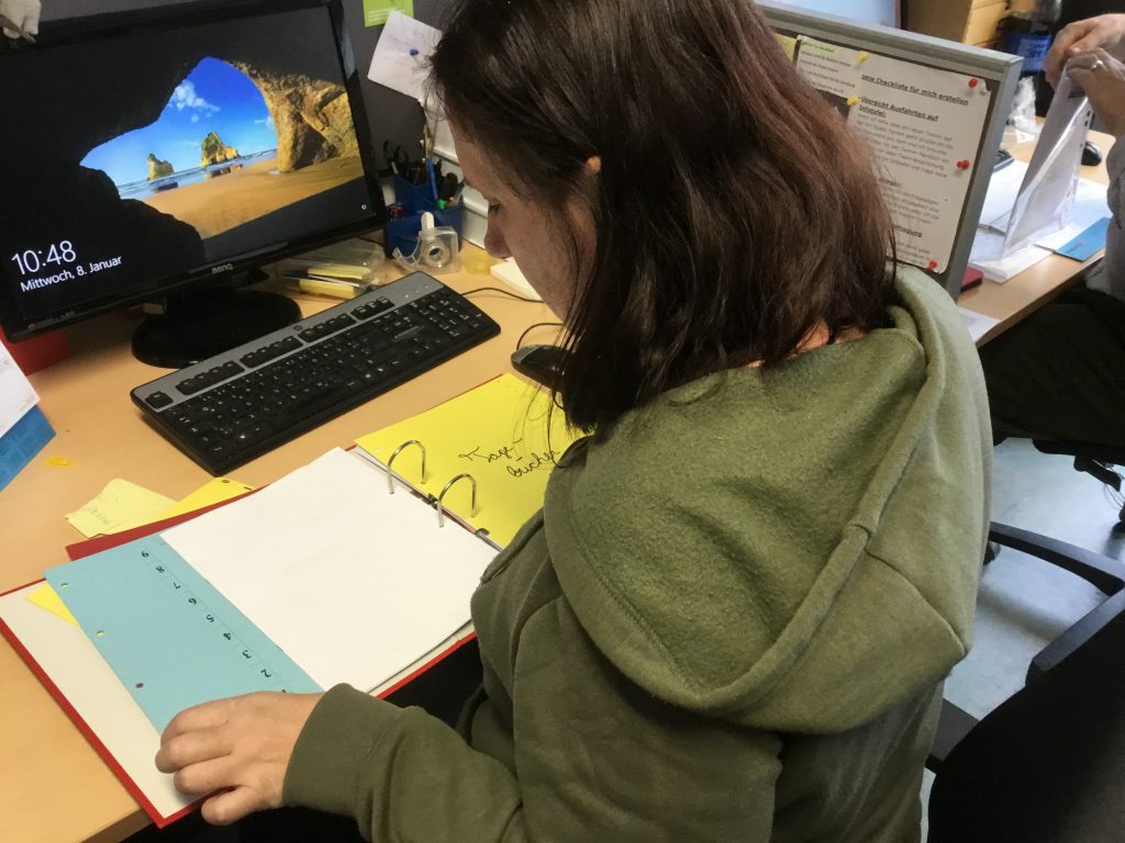 Girl sitting at a desk looking down at a folder in front of her