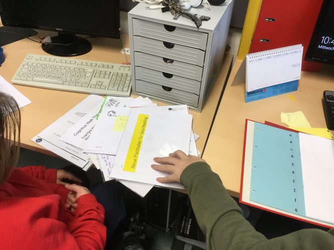 Two women sit at their desks and sort documents