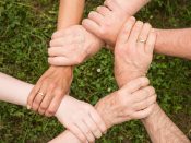 Foto von sechs Händen, die sich gegenseitig an den Handgelenken festhalten und so einen Kreis aus Händen und Armen bilden.